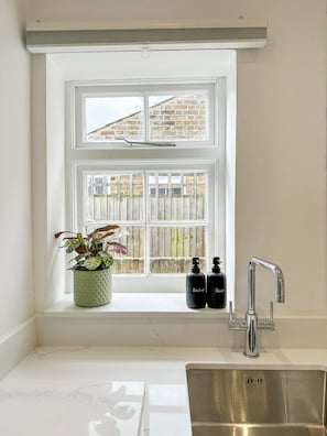 A kitchen with a window, a sink, and two bottles on the windowsill.
