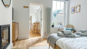 A bedroom with a bed, a TV, a radiator, and a window with curtains.
