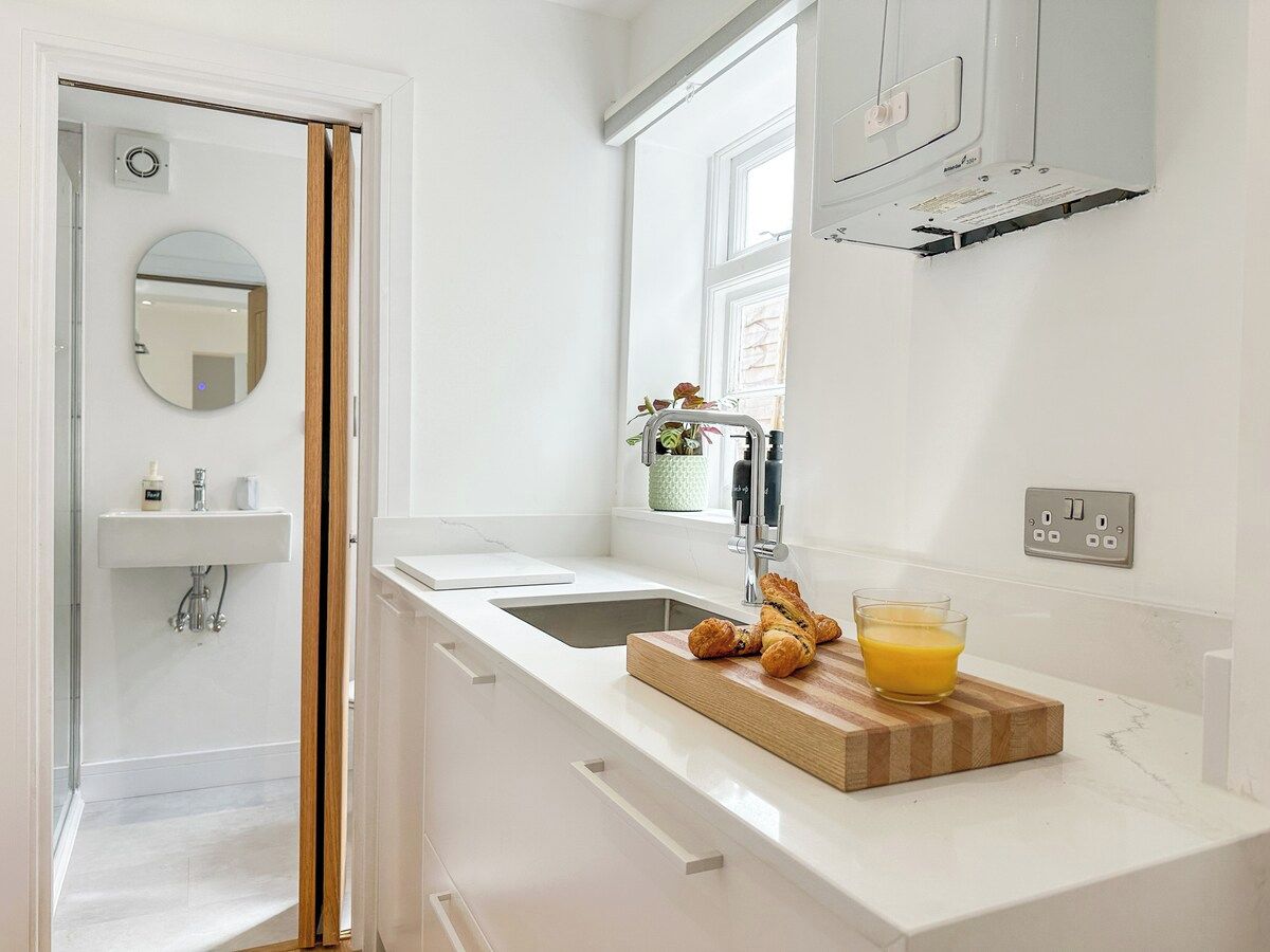 Una cocina moderna con encimera blanca, un lavamanos, una ventana y un espejo.