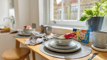 A kitchen counter with a bowl of food, a mug, and a potted plant.