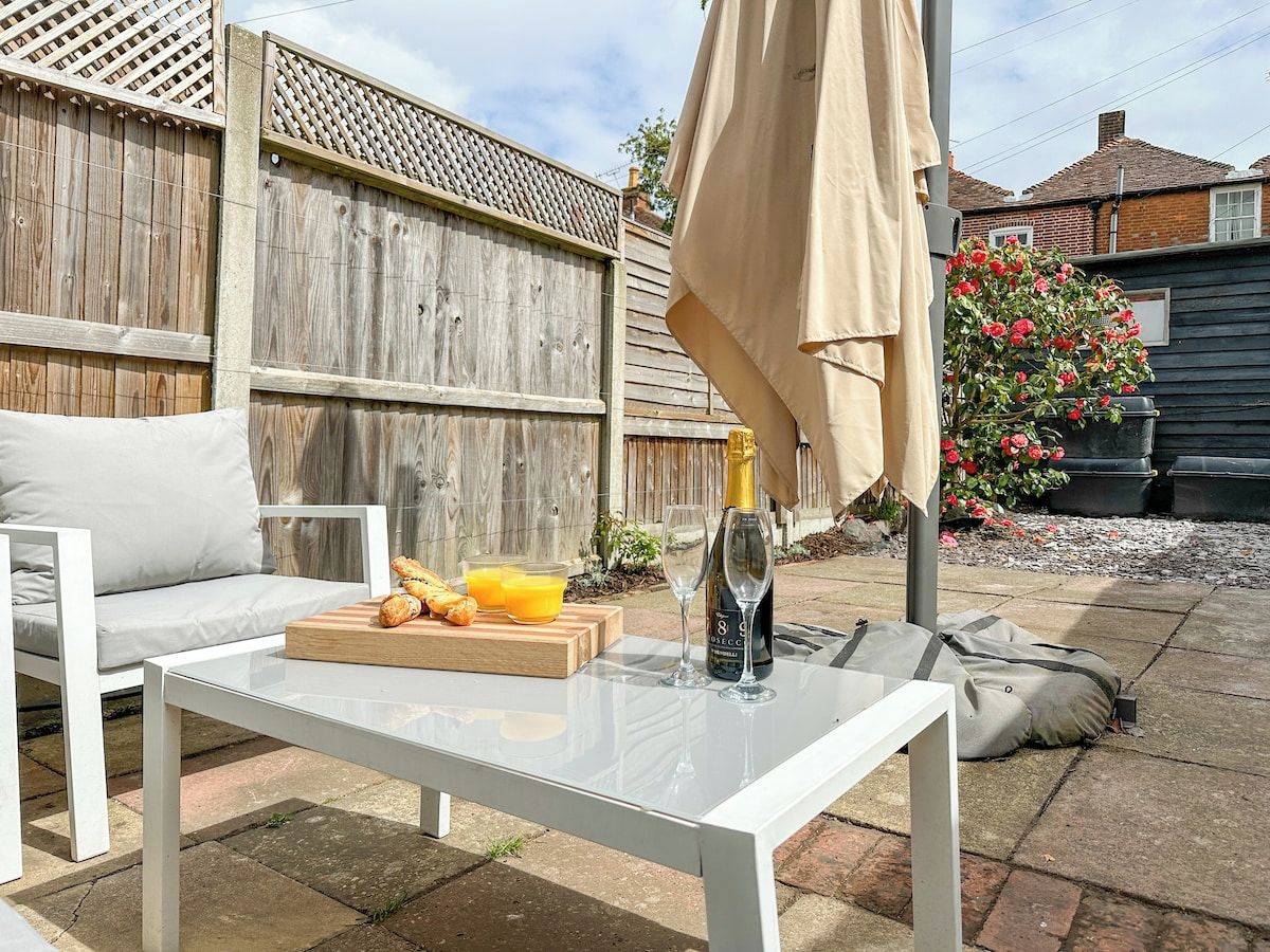 A patio with a white table, a bottle of champagne, and a glass of orange juice.