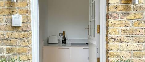 A doorway leading to a kitchen with white cabinets, a countertop, and a bottle of champagne.