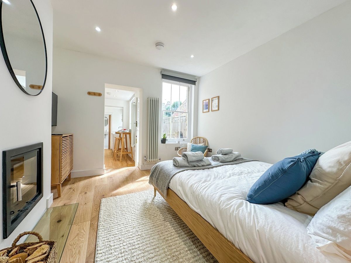 A bedroom with a bed, a fireplace, a window, and a view of the outside.