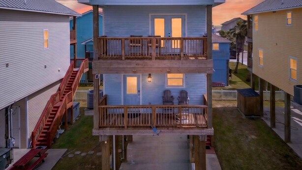 A two-story building with a balcony, a staircase, and a small outdoor seating area. - Steps to the Beach, Stunning Sunrises and Sunsets! (Galveston)