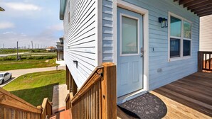 A residential house with a front door, a small porch, and a visible street. - Steps to the Beach, Stunning Sunrises and Sunsets! (Galveston)
