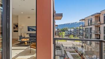 A modern apartment with a balcony, a living room with a sofa and coffee table, and a mountain view.