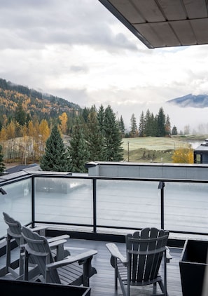 Une terrasse avec des chaises donnant sur un plan d’eau, des arbres et une chaîne de montagnes lointaine.