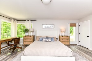 Ein Schlafzimmer mit einem großen Bett, zwei Nachttischen, einem Schreibtisch und einem Stuhl.