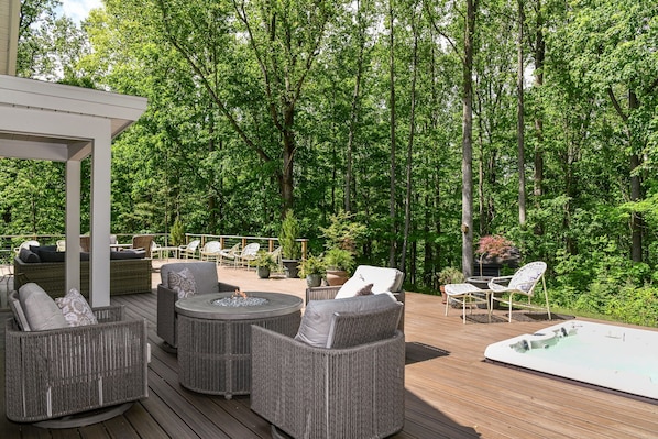 An outdoor deck with wicker furniture, a hot tub, and a pergola.
