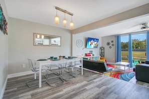 Ein modernes Wohnzimmer mit Essbereich, großen Fenstern und Blick ins Freie.