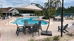 Ein Poolbereich mit Tisch und Stühlen, einer überdachten Sitzgelegenheit und einem Pool mit einer Fliesenbordatur.
