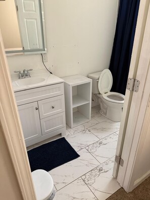 Un baño con lavamanos, tocador y retrete blancos.