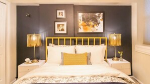 A bedroom with a bed, two bedside tables, a headboard, and wall art. - Chic Downtown Denver Retreat | Walk Everywhere + Stylish Comfort (Denver)