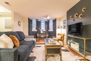 En stue med sofa, sofabord, TV-møbel og et spiseområde med stole og bord.
