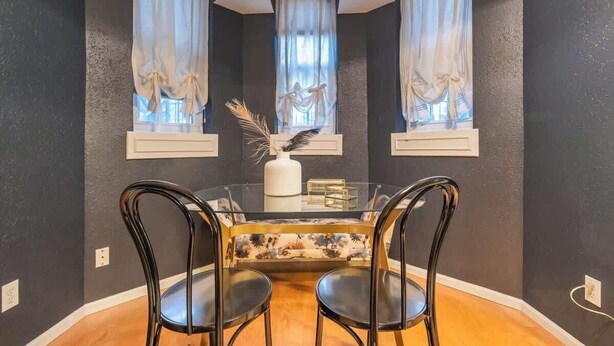 A dining area with a glass table, two black chairs, and a floral sofa. - Chic Downtown Denver Retreat | Walk Everywhere + Stylish Comfort (Denver)