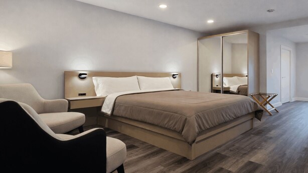 A modern hotel room with a large bed, a chair, a bedside table, and a mirror. - Modern Ground Floor Studio w/ Patio & Kitchen (Freeport)
