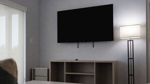 Ett modernt rum med en platt-TV som är monterad på väggen, en golvlampa, ett bord med en skiva av marmor och en stilren möbel för underhållningssystemet.