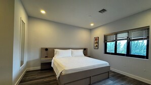 A bedroom with a bed, nightstands, a window with blinds, and a picture on the wall. - Relaxing 1-Bedroom Suite w/ Balcony & Sleeps 4 (Freeport)