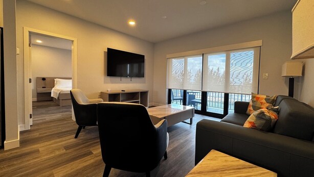 A modern living room with a sofa, chairs, a TV, and a dining area. - Relaxing 1-Bedroom Suite w/ Balcony & Sleeps 4 (Freeport)