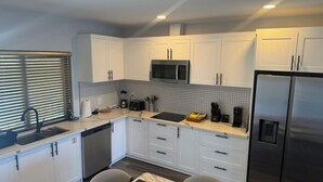 Una cocina moderna con armarios blancos, un refrigerador de acero inoxidable, un microondas y un lavavajillas.