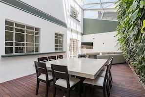A modern outdoor dining area with a white table and chairs, a wooden deck, and a green wall with plants. - Art Déco Condesa II Stylish and quiet with rooftop (Ciudad de México)