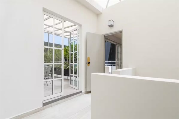 A modern interior with a glass door leading to an outdoor area, a white wall, and a ceiling with skylights. - Art Déco Condesa II Stylish and quiet with rooftop (Ciudad de México)