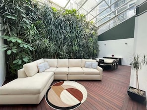 A modern interior with a sectional sofa, a dining table, and a large plant wall. - Art Déco Condesa II Stylish and quiet with rooftop (Ciudad de México)