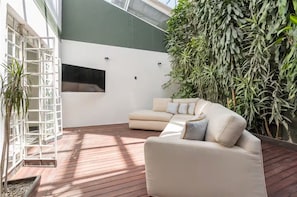 A modern interior with a beige sofa, a white wall-mounted TV, and a large green plant wall. - Art Déco Condesa II Stylish and quiet with rooftop (Ciudad de México)