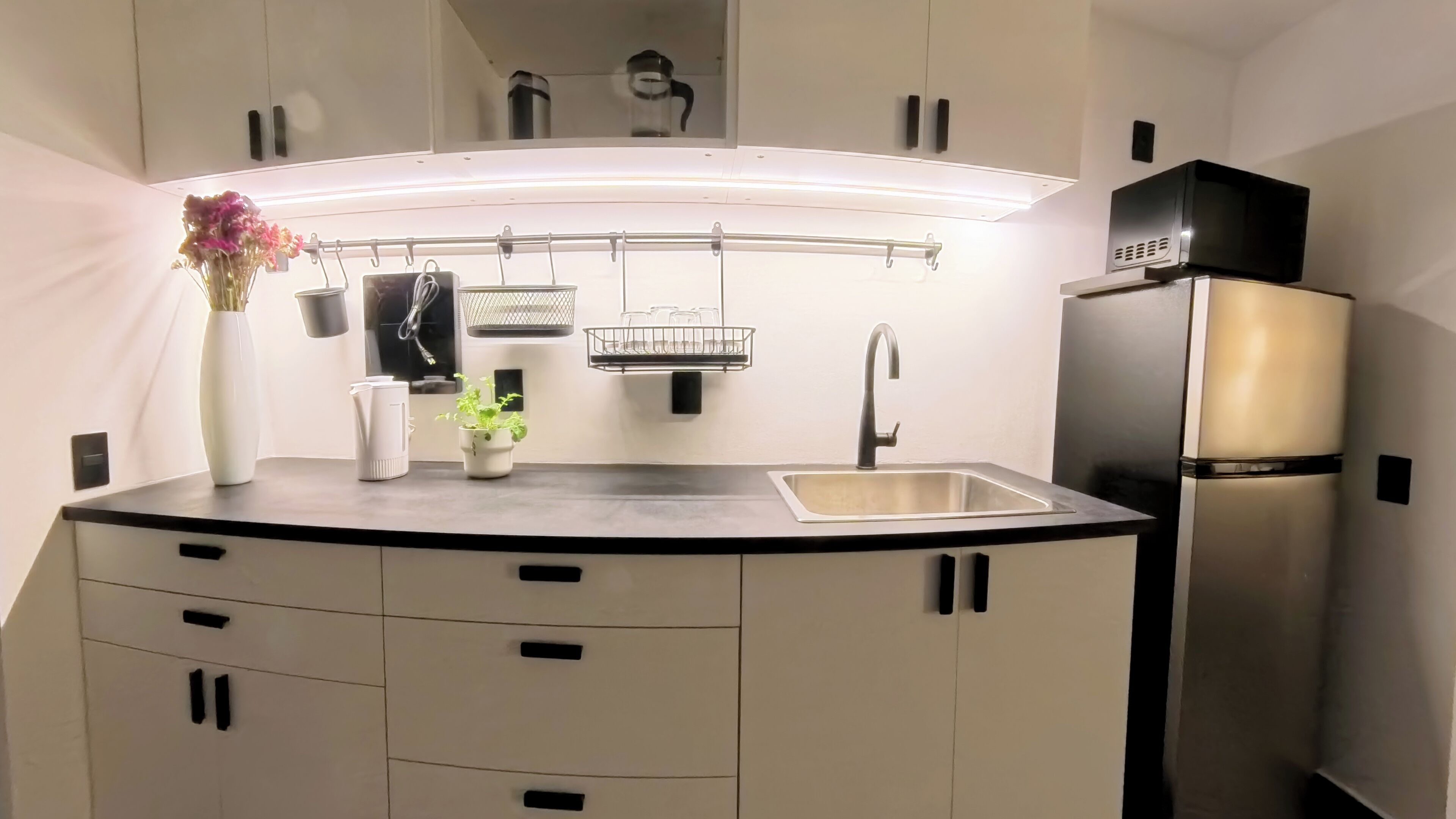 Una cocina moderna con un lavamanos empotrado, un refrigerador de acero inoxidable y una encimera con un florero.