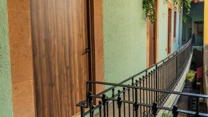 A building with a wooden door, a balcony with a wrought iron railing, and a green wall with hanging plants. - Straw Hat Hostel & RoofTop Bar CDMX (Mexico City)