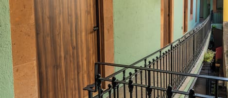 Un bâtiment doté d’une porte en bois, d’un balcon orné d’une rambarde en fer forgé et d’un mur végétal agrémenté de plantes suspendues.