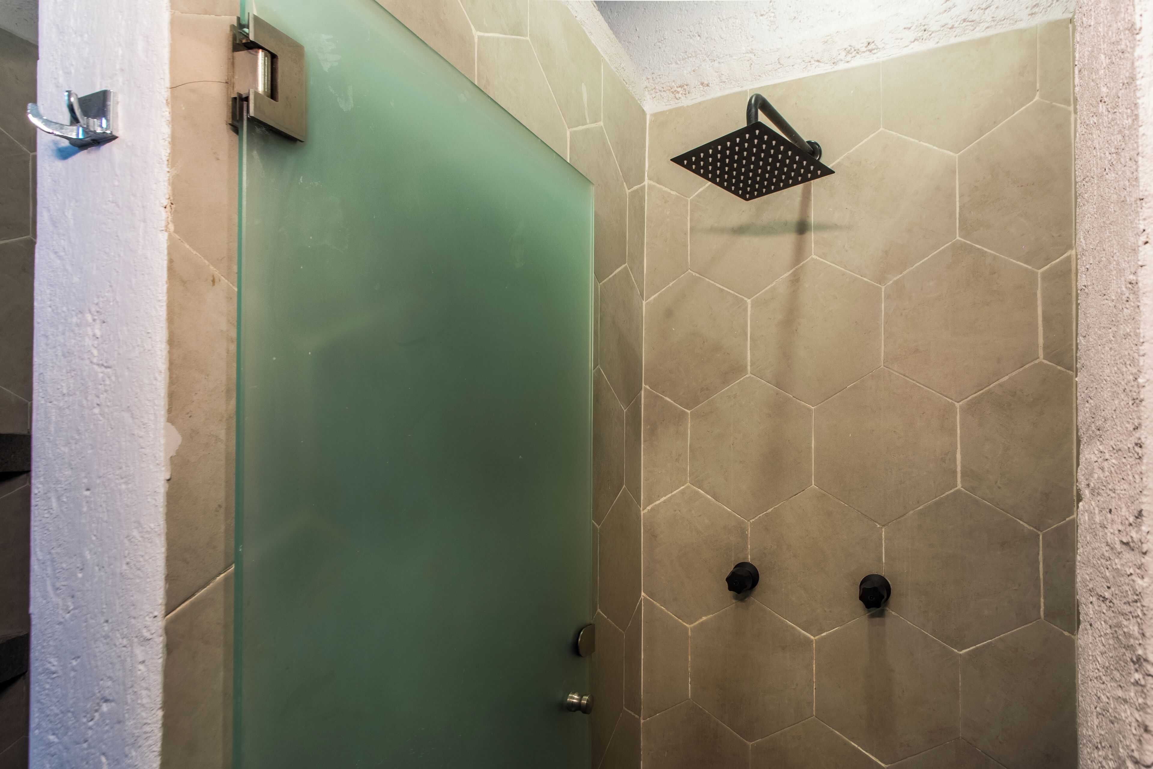 A shower area with a hexagonal tile pattern and a green door.