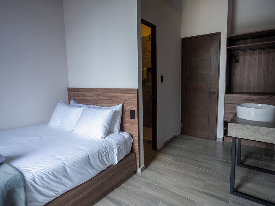 A hotel room with a bed, a bathroom with a sink, and a door leading to another room.
