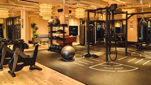 Un gimnasio con equipo de ejercicio, suelo de madera y un rack de pesas montado en la pared.