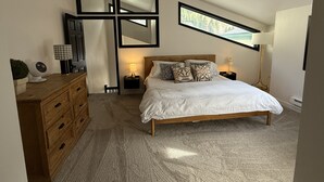 Ein Schlafzimmer mit Bett, Schminktisch, Nachttisch, Lampe und Spiegel.