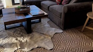 Ein modernes Wohnzimmer mit einer Ledersofa, einem Couchtisch, einem Teppich und Blick ins Freie.