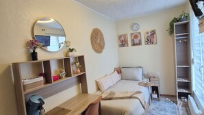 A bedroom with a bed, a desk, a chair, a round mirror, a clock, and a shelf with decorative items. - Independent studio (Châlons-en-Champagne)