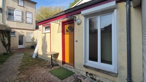 A residential building with a red door, a window with white frames, and a small outdoor seating area. - Independent studio (Châlons-en-Champagne)