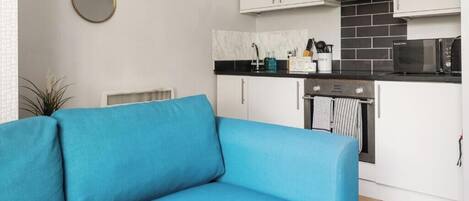 Una cocina moderna con armarios blancos, encimera negra y un microondas.