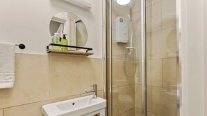 Ein Badezimmer mit einer gläsernen Dusche, einem weißen Waschbecken und einem Spiegel darüber.