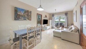 Amplia sala de estar con mesa de comedor, sillas, sofá y televisor.