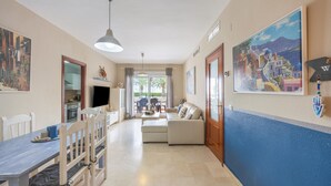 Amplia sala de estar con mesa de comedor, sillas, sofá y televisor.