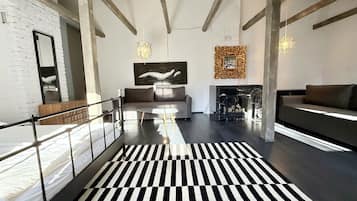 A modern interior with a black and white striped floor, a sofa, a fireplace, and a large abstract painting.