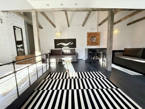 Un intérieur moderne avec un sol rayé de noir et de blanc, un canapé, une cheminée et un grand tableau abstrait.