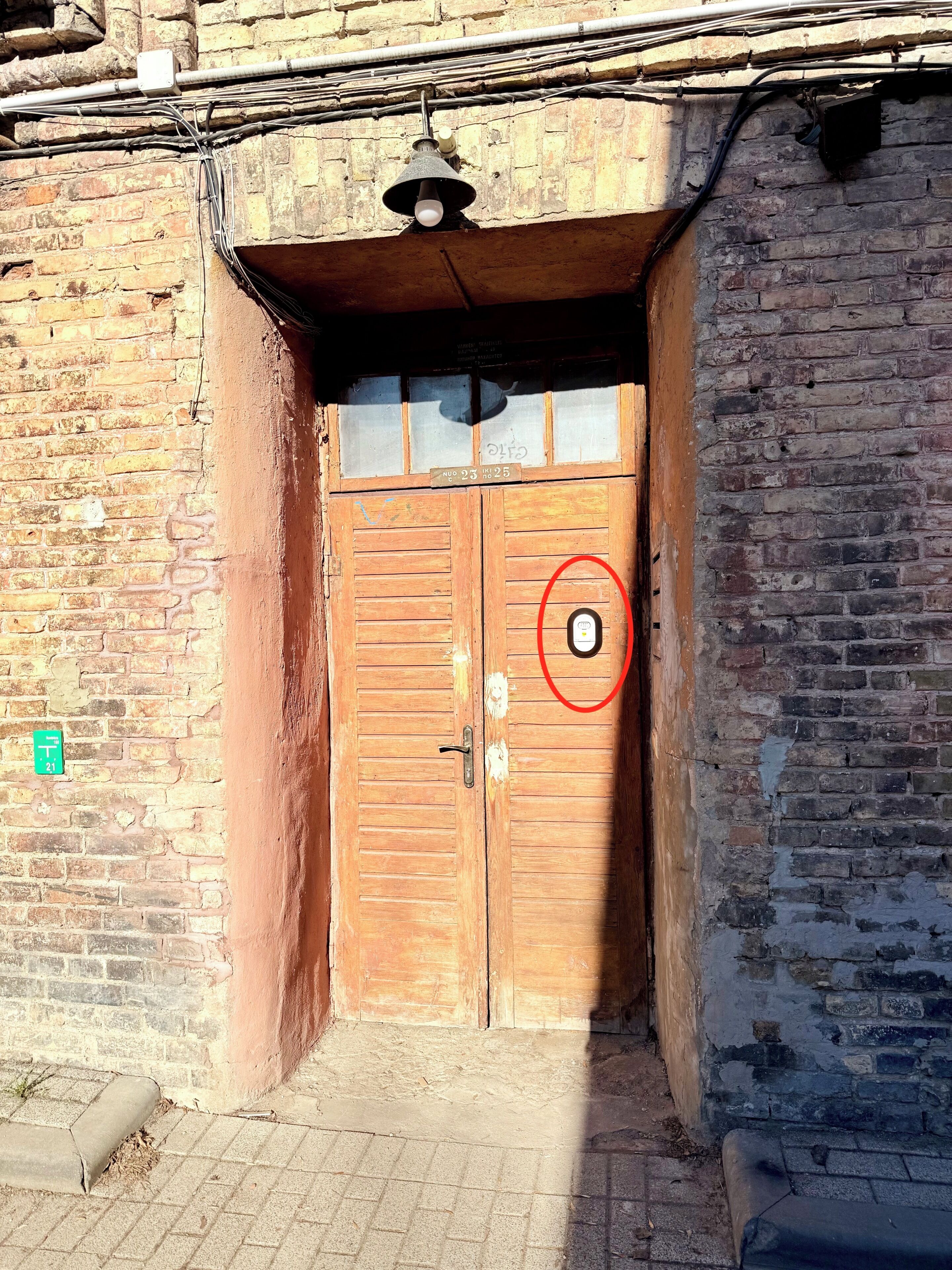 A wooden double door with a small window above it, a metal handle, and a red circle marking a specific spot on the door.