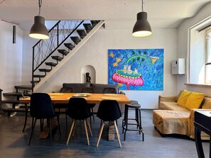 A modern interior with a dining area, staircase, and artwork. - Uzupio2 Old Town Studio (Vilnius)