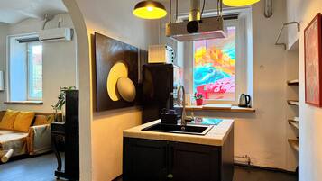 A modern kitchen with a central island, pendant lighting, and a colorful window view.