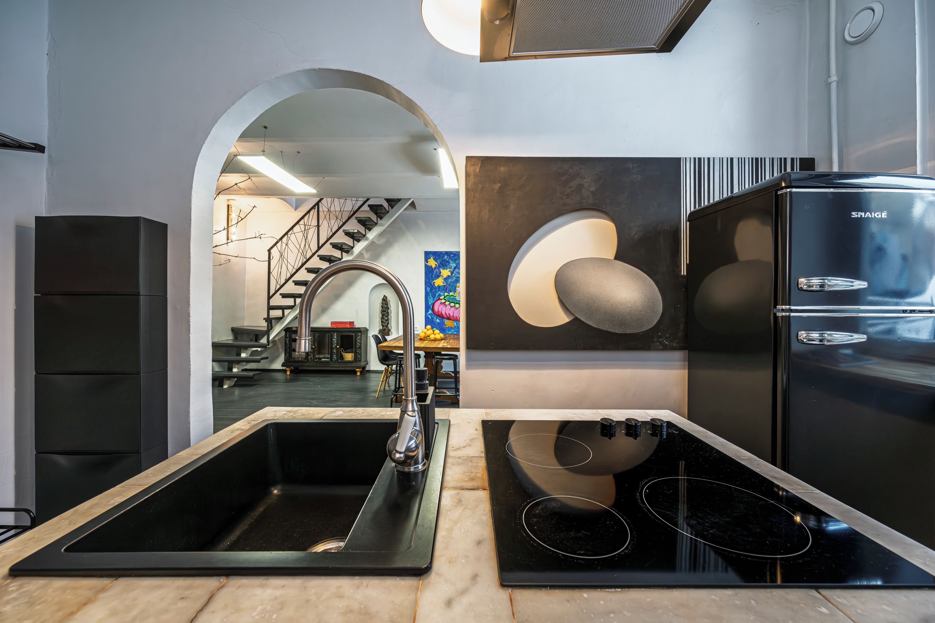 A modern kitchen with a built-in sink, a black stove, and a refrigerator.