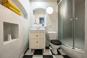 A bathroom with a white vanity, a toilet, a shower enclosure, and a marble-framed mirror. - Uzupio2 Old Town Studio (Vilnius)