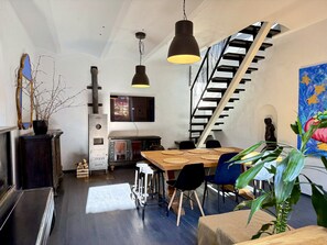 Un intérieur moderne avec un escalier, un coin repas doté d’une table en bois et un grand tableau.
